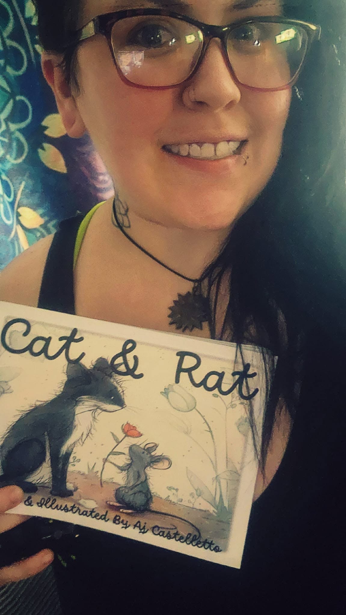 Aj Castelletto holding a copy of Cat & Rat, smiling